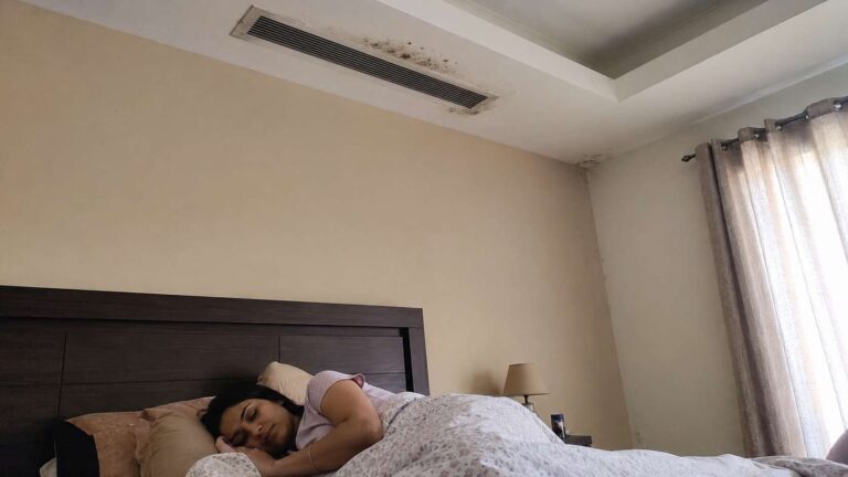 A woman sleeping below a moldy ac vent