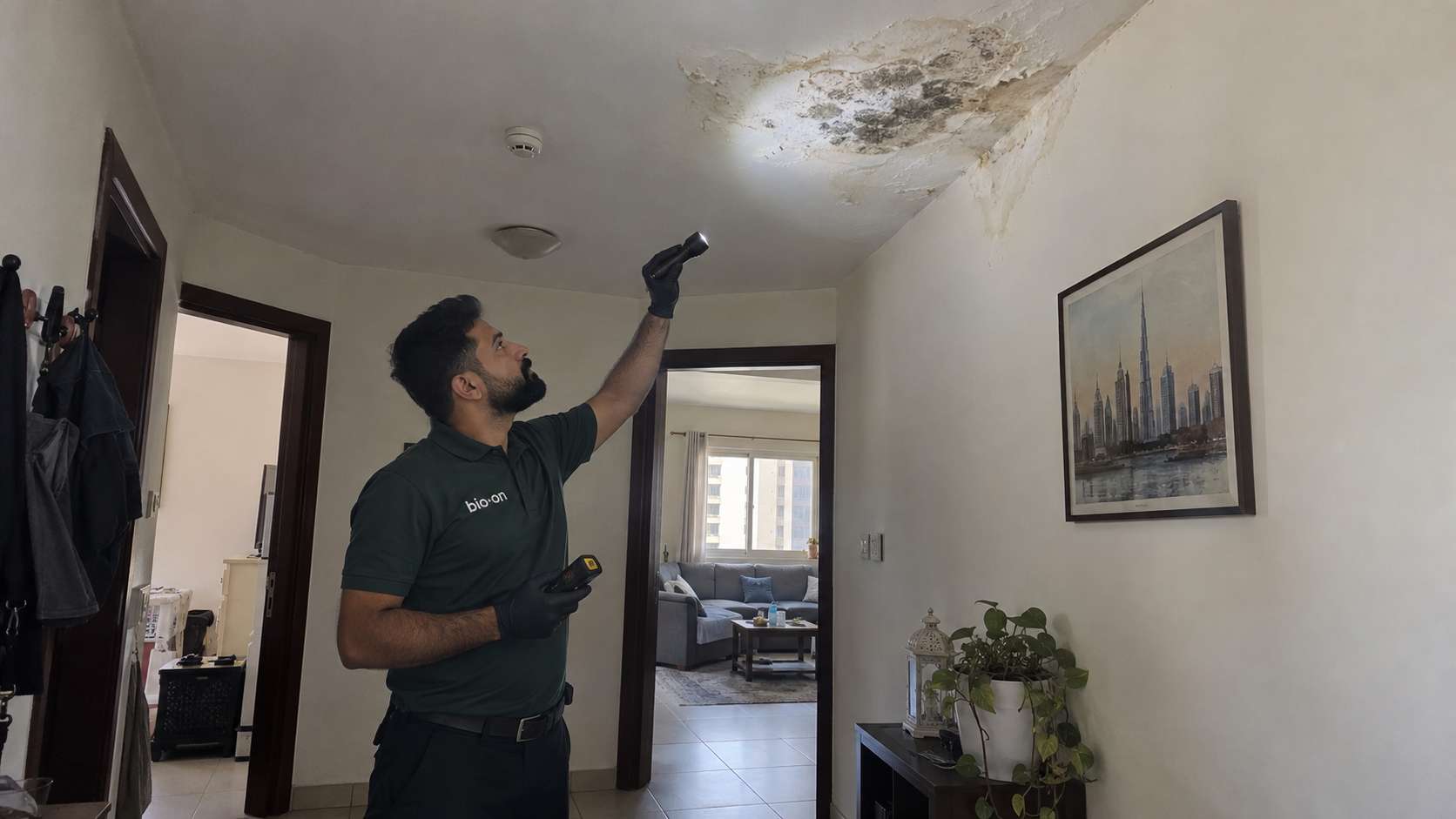 Bio-On technician inspecting mold and water damage high on a ceiling in a UAE apartment