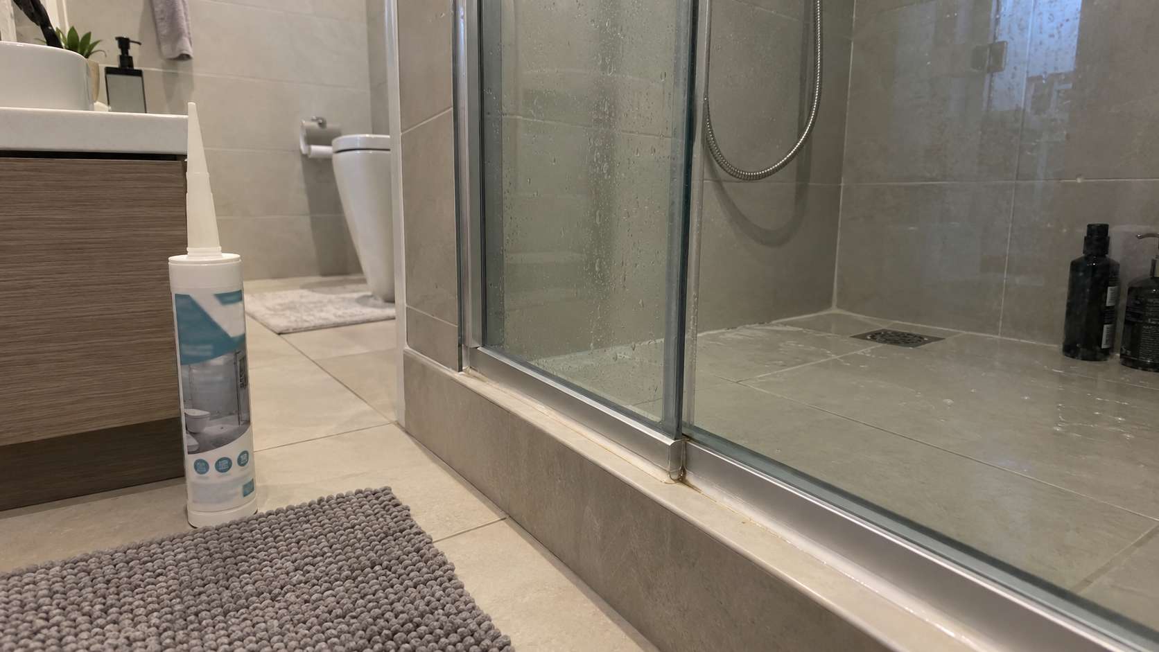 Sanitary silicone sealant beside a shower joint in a UAE bathroom with minor mold discoloration