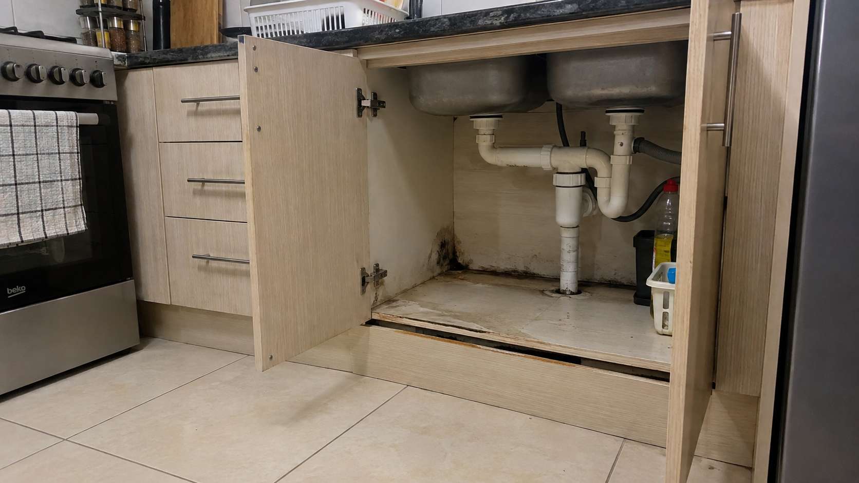 Slow hidden leak causing moisture and mold inside a kitchen cabinet in a UAE home