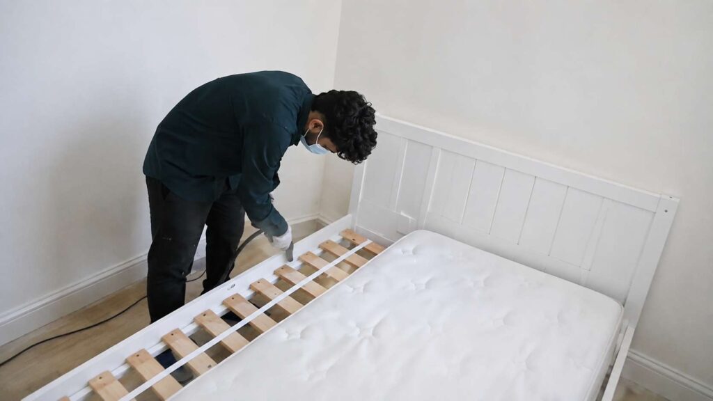 Mold cleaning specialist from Bio-on is spraying anti-mold mist along the bed frame