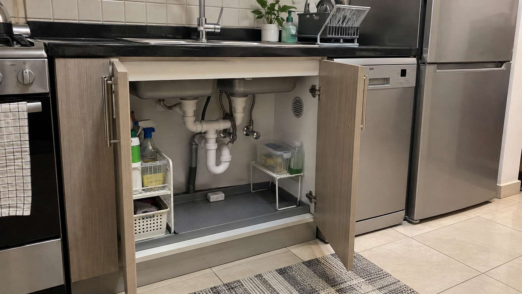 Under-sink cabinet with leak sensor, accessible plumbing, and moisture-resistant base in a UAE kitchen