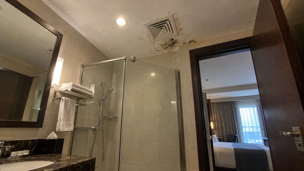 Mold and moisture damage around the ceiling of a hotel bathroom