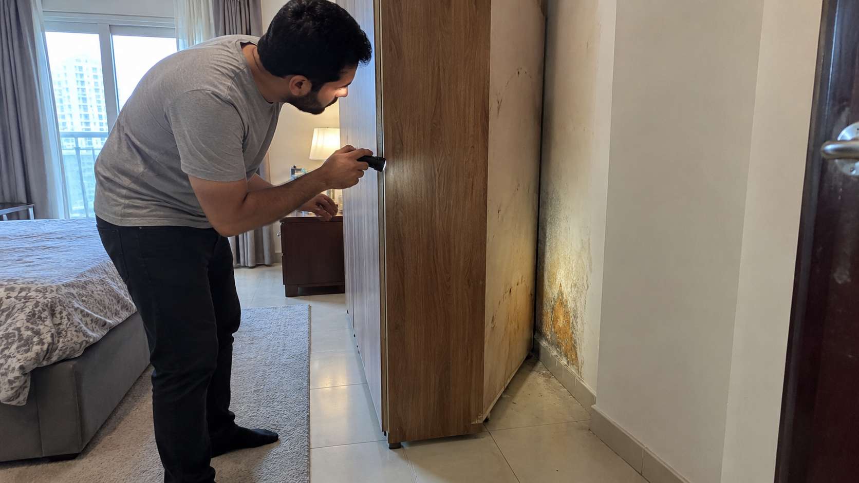 Orange mold growing on a damp wall hidden behind a wardrobe in a UAE bedroom