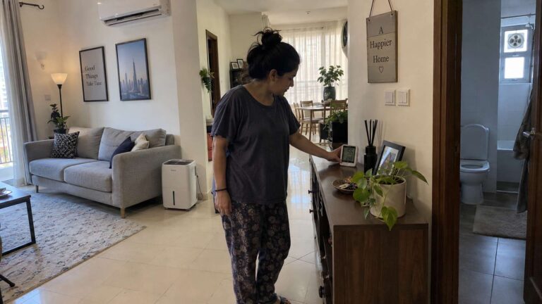 UAE homeowner checking indoor humidity in a well-ventilated mold-resistant home with smart furniture spacing