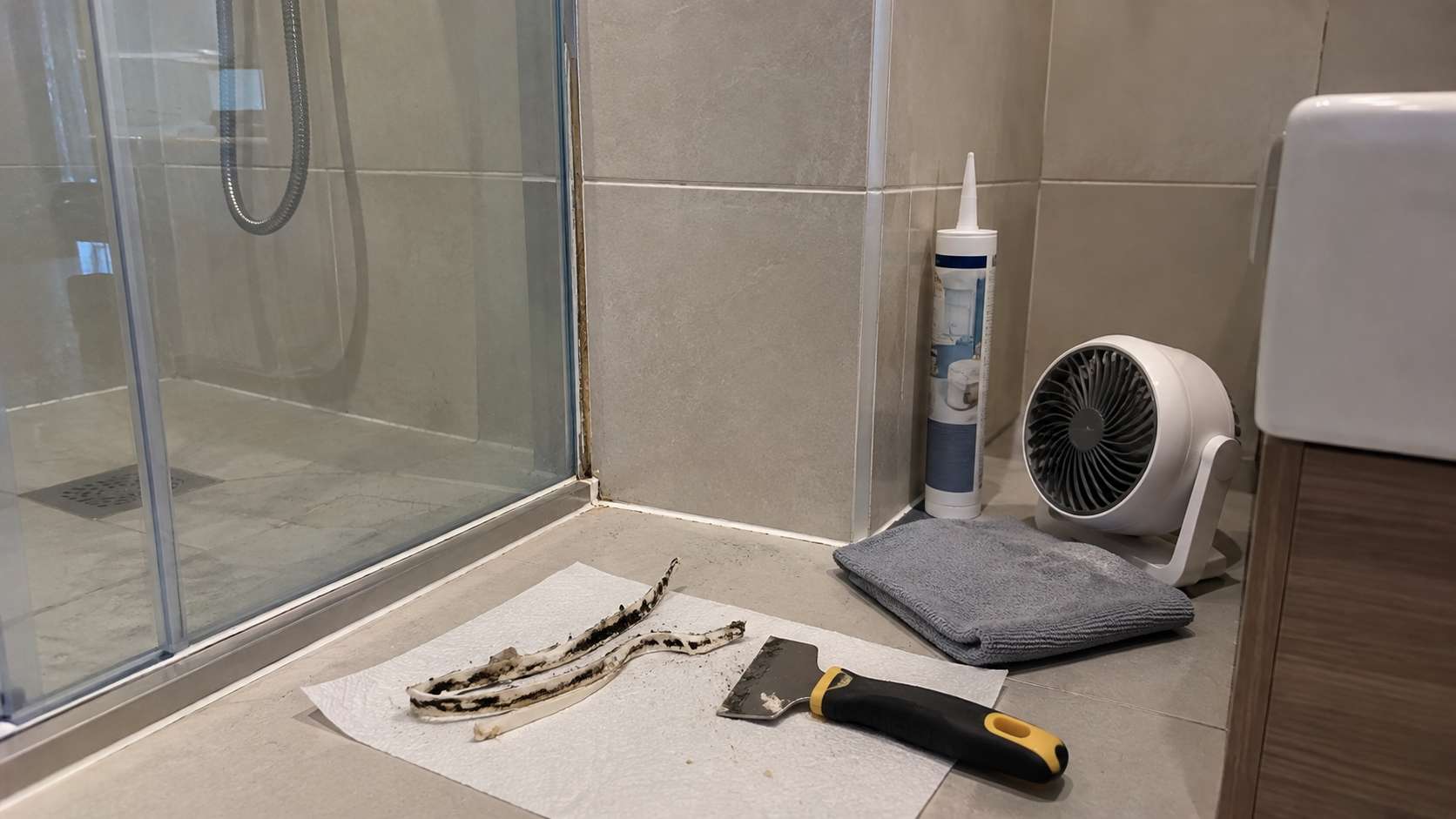 Old moldy caulk removed and clean dry shower joint prepared for new sanitary silicone