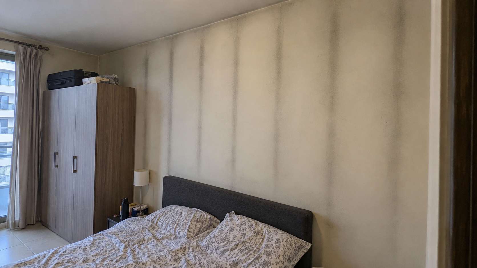 Dry black ghosting marks following wall studs and furniture outlines in a UAE apartment
