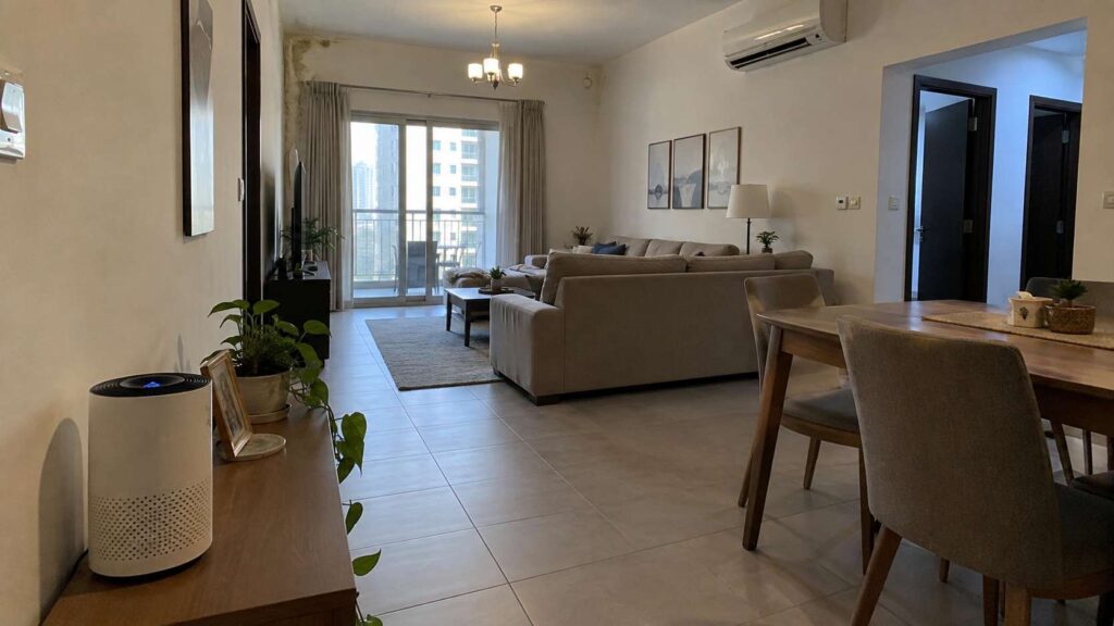 Small air purifier operating in a large UAE living room with a distant moisture-related wall concern
