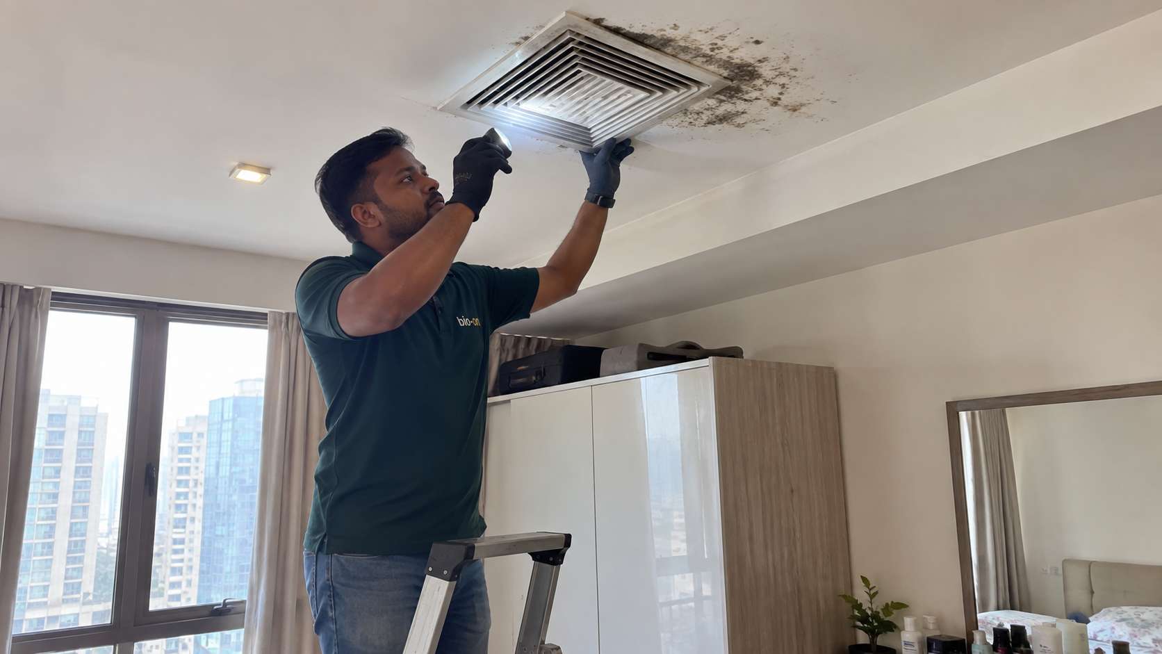 Bio-On technician inspecting mold around a ceiling AC vent in a UAE home.