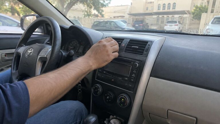 Driver adjusting a dusty car AC vent as condensation and moisture clues suggest a musty HVAC odor problem.