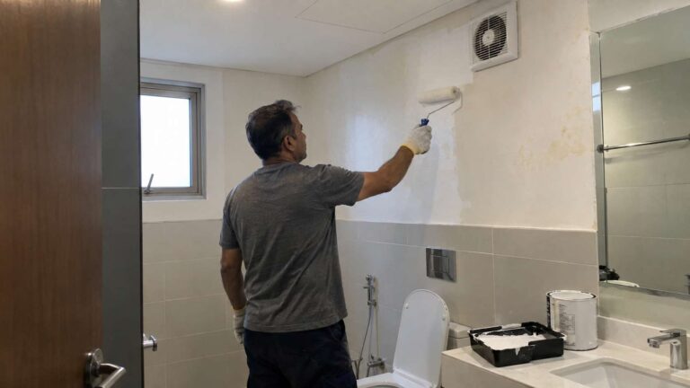 Primer being rolled onto a clean dry bathroom wall after moisture correction.
